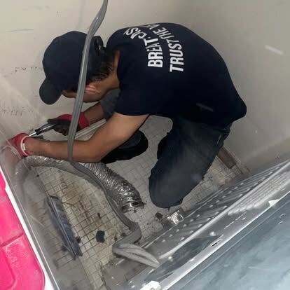 dryer vent cleaning: a technician cleaning the dryer vent connection at the appliance