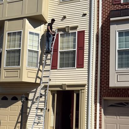 dryer vent cleaning guide: a technician using professional ladder access for an upper-level exterior vent