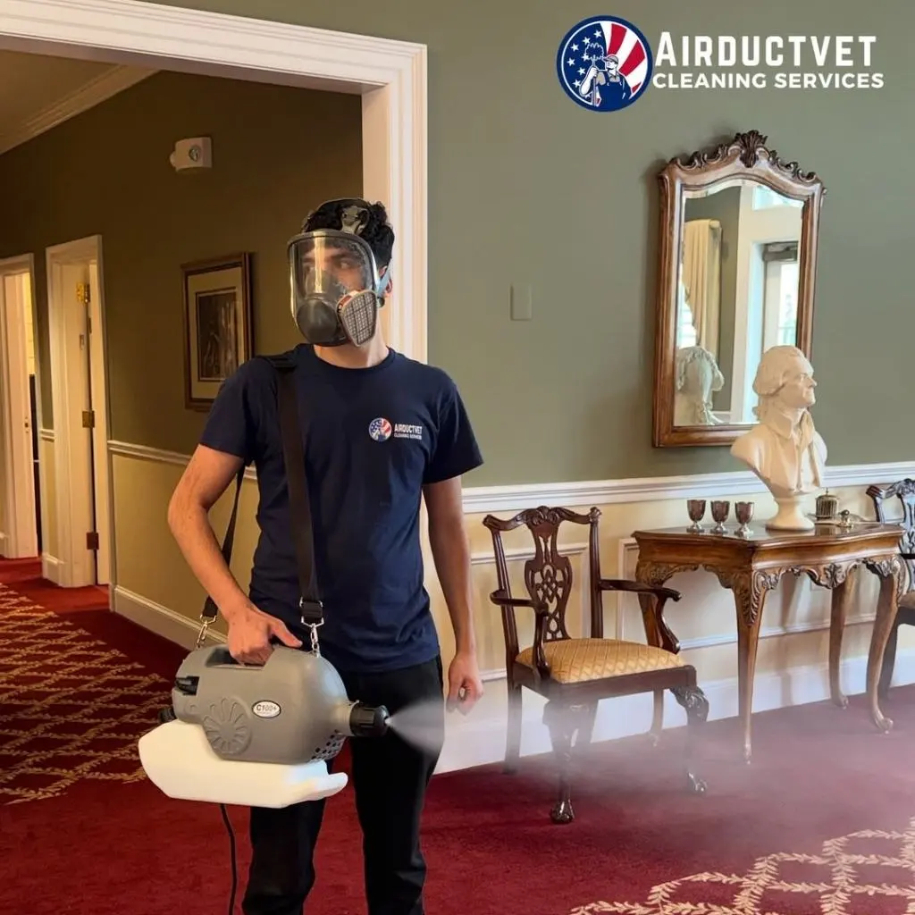 Technician wearing protective gear while sanitizing HVAC systems inside a home.