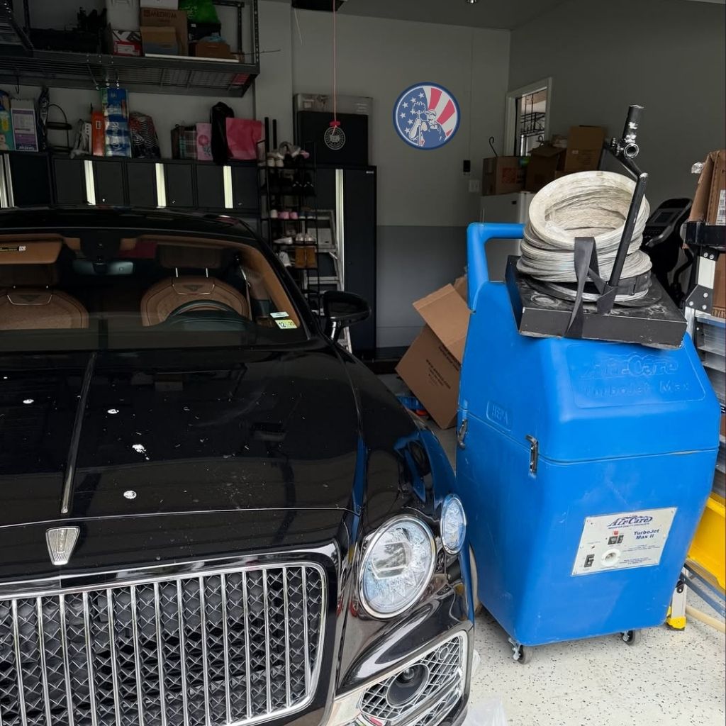 Duct cleaning equipment stored in garage next to luxury vehicle in Alexandria VA
