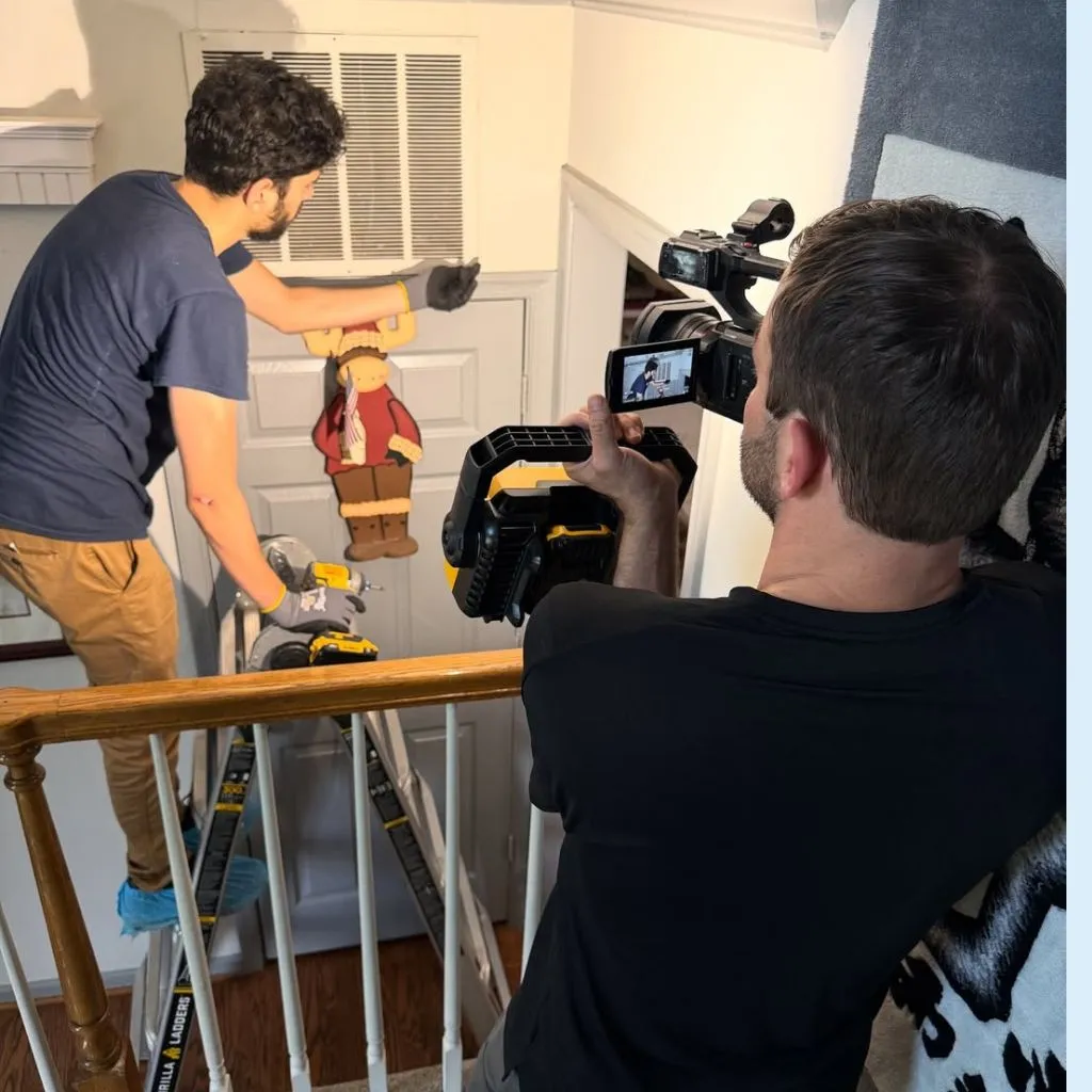 Case study dryer vent cleaning in Alexandria VA showing AirDuctVet technician on a ladder using professional rotary brush tools while being filmed for documentation.