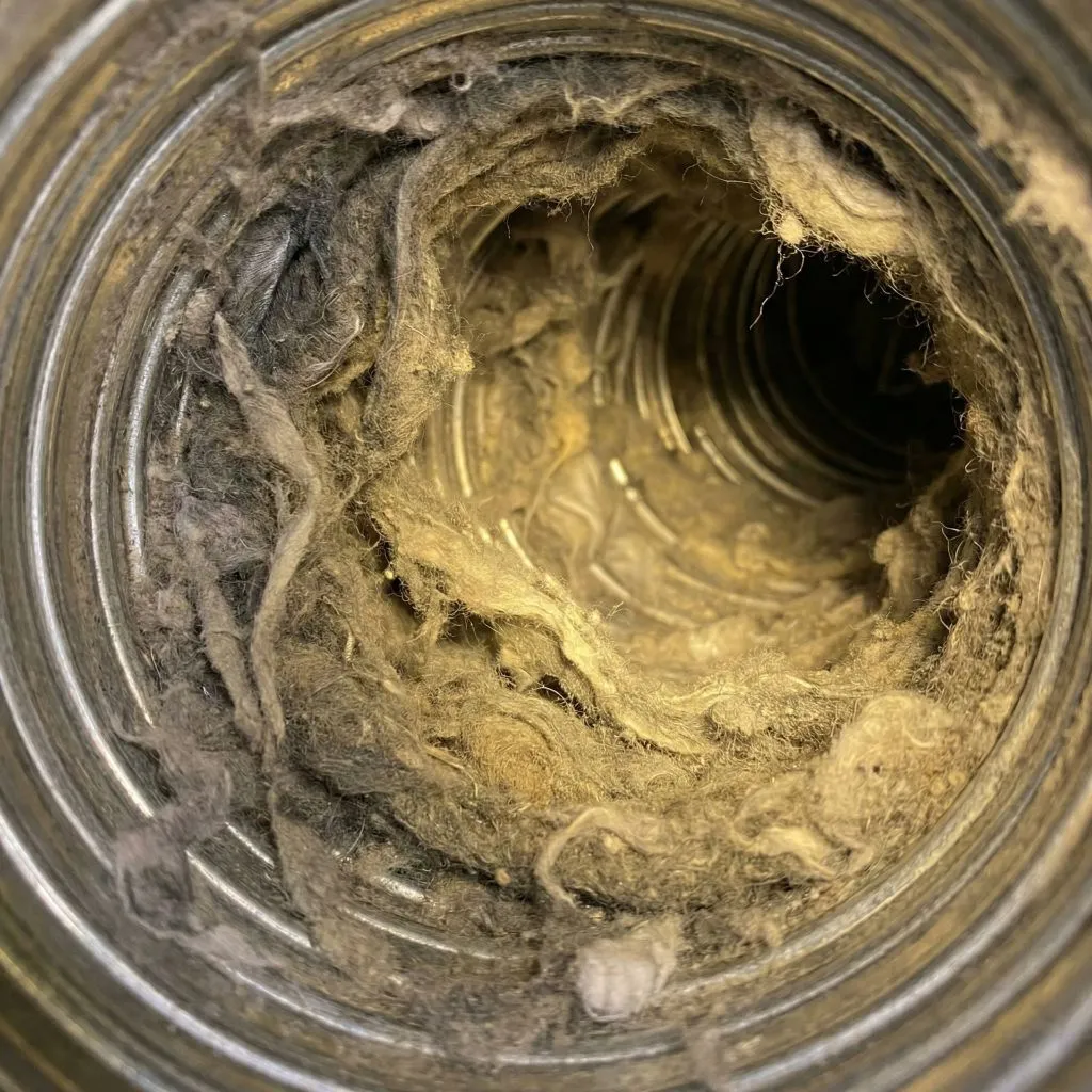 Interior of a flexible dryer vent completely clogged with debris, illustrating the serious dryer vent lint health impact caused by trapped exhaust and moisture.