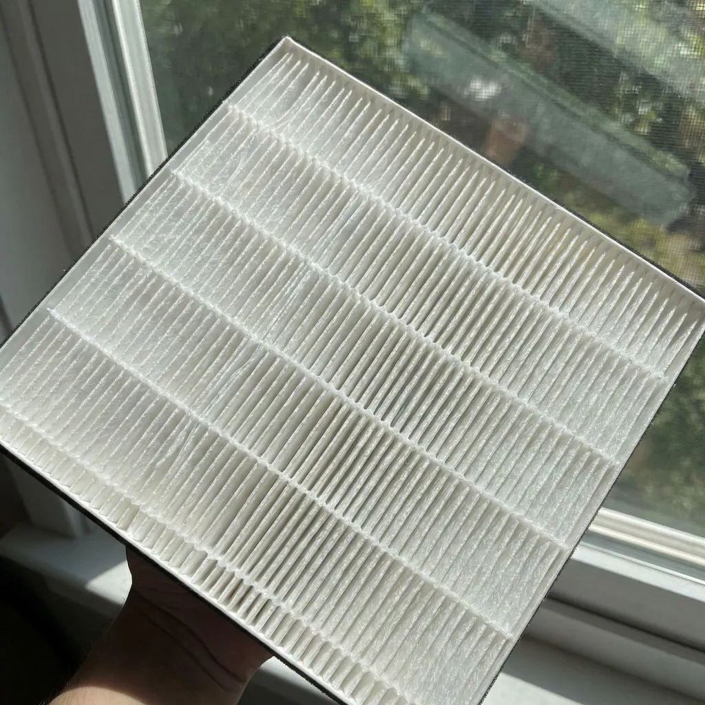 Hand holding a clean, pleated air filter against a window, demonstrating the maintenance required for allergy-proof home air ducts.
