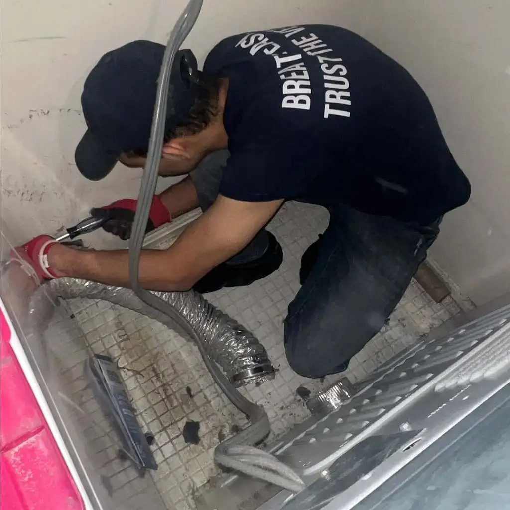 AirDuctVet technician kneeling to connect flexible ducting inside crawlspace during Raleigh Durham Triangle duct cleaning job